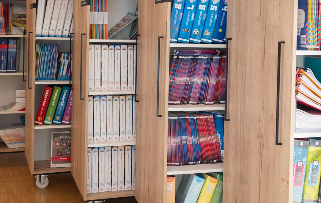 Op de afbeelding zie je 3 verrijdbare boekenkasten met methodeboeken.