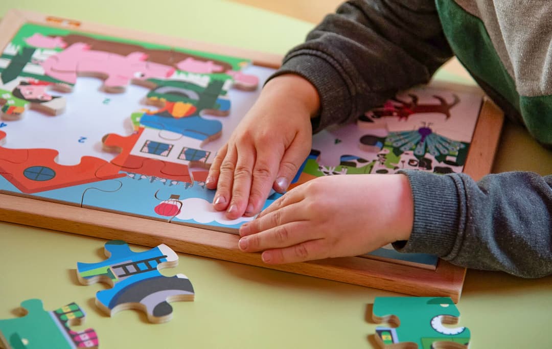 Afbeelding waarbij een jongetje een puzzel in elkaar legt.