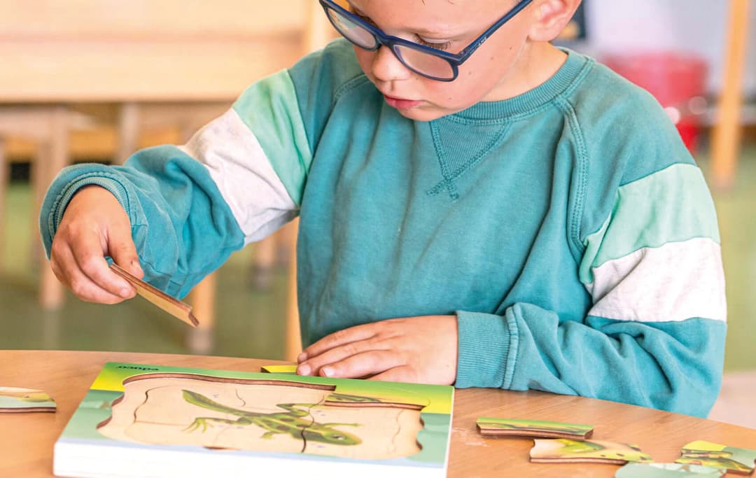 De jongen op de afbeelding is een puzzel aan het leggen.