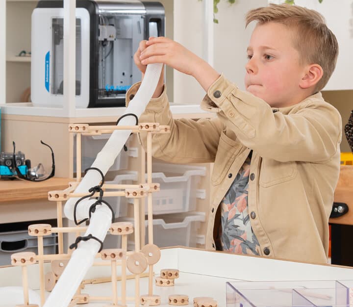 Jongen is aan het spelen met loose parts set in de techniek hoek.