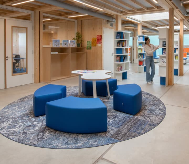 Op de afbeelding zie je een kindercentrum met een wolkentafel en blauwe poefjes.