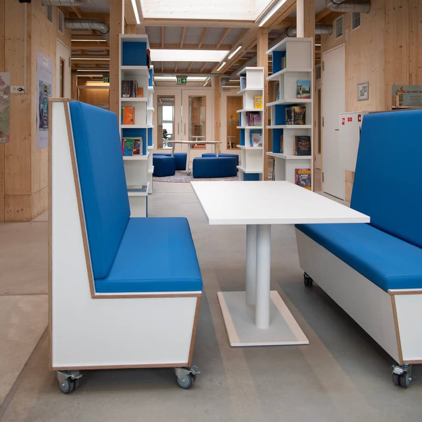 Op de afbeelding zie je een grote ruimte met een tafel en treinbanken.