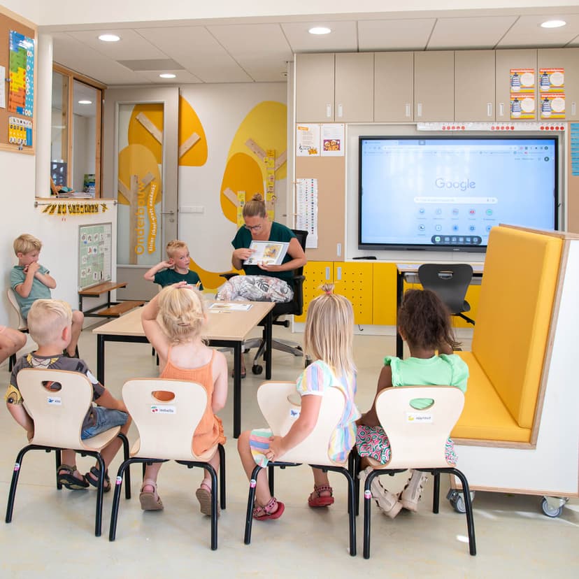 Op de afbeelding zie je de rug van een treinbank en een kast op maat met digibord middenin.