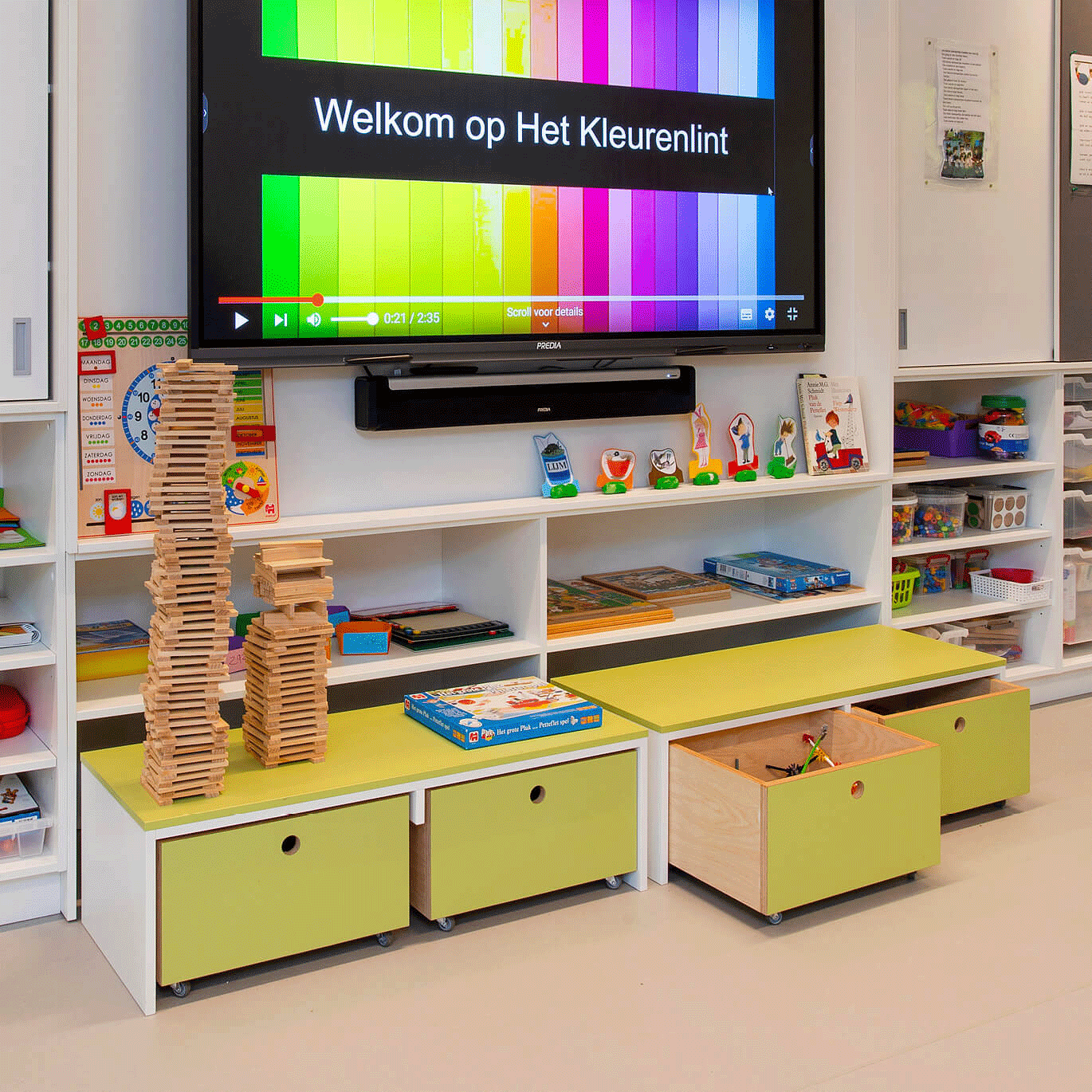 OP de afbeelding zie je een open kast tegen de muur met groene uitschuifbare laadjes.