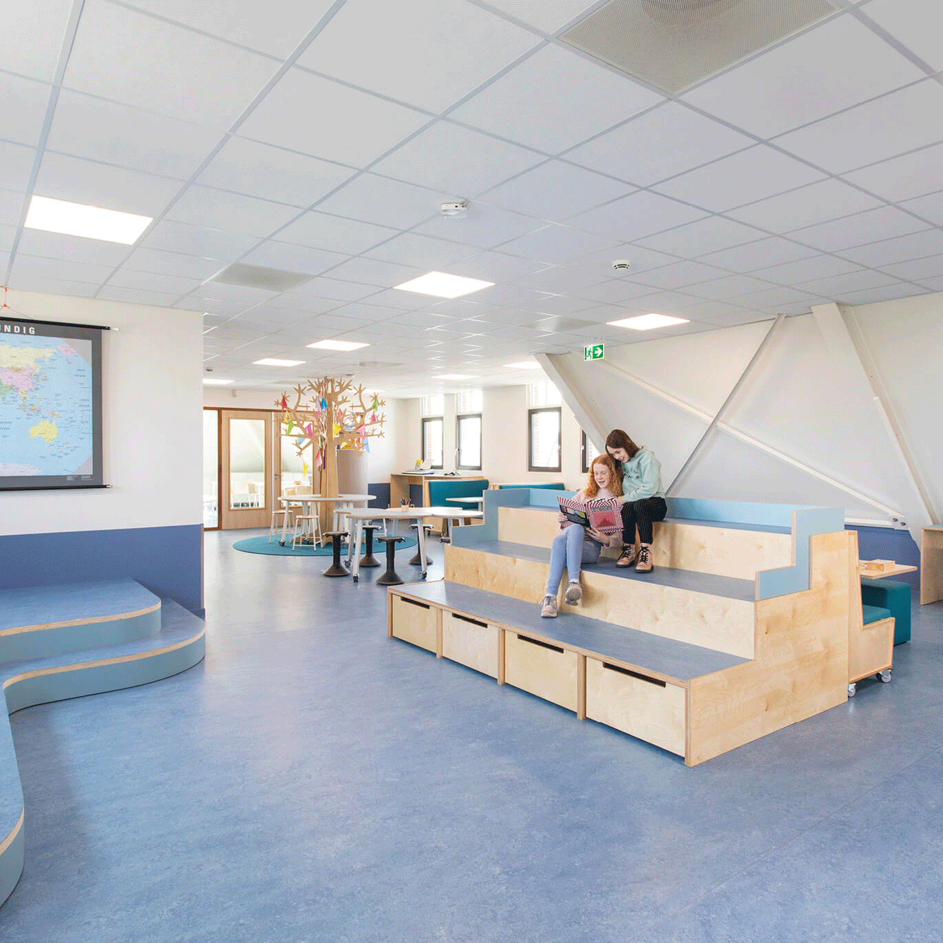 Op de afbeelding zie je een leerplein met treinbanken en ook hoge tafels.