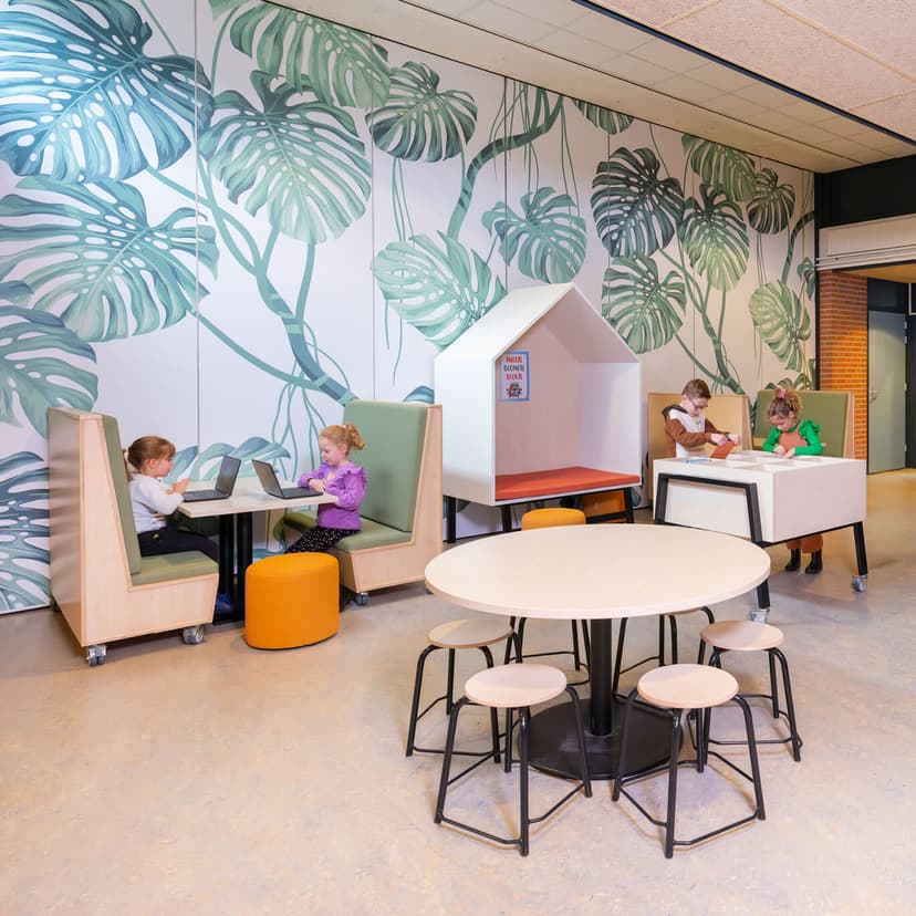 Op de afbeelding zie je kinderen die op een treinbankje zitten te leren.